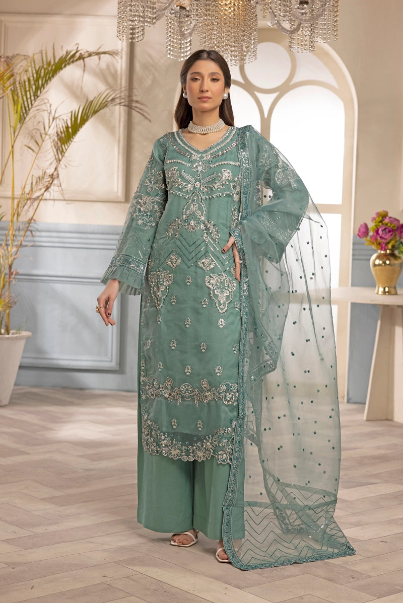 Woman wearing a green embroidered traditional outfit in an elegant room.