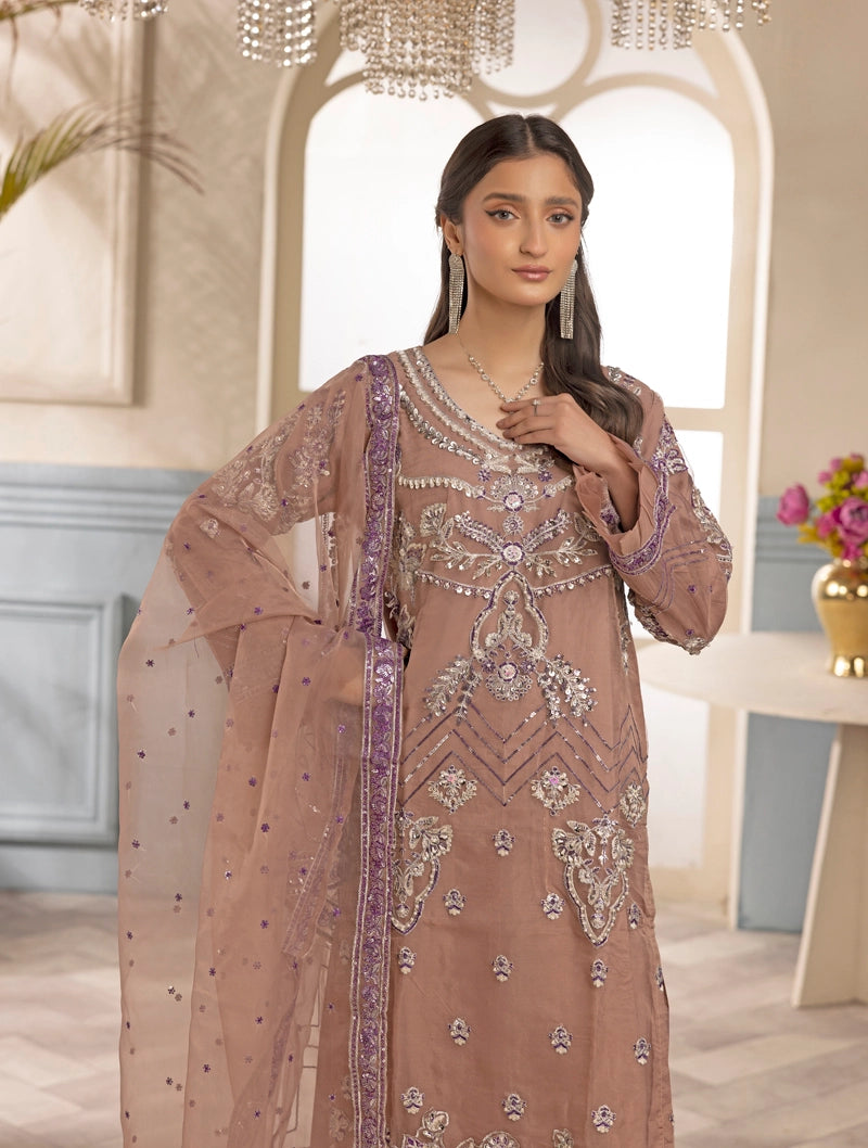 Woman wearing an embroidered pink traditional outfit in a decorated room.