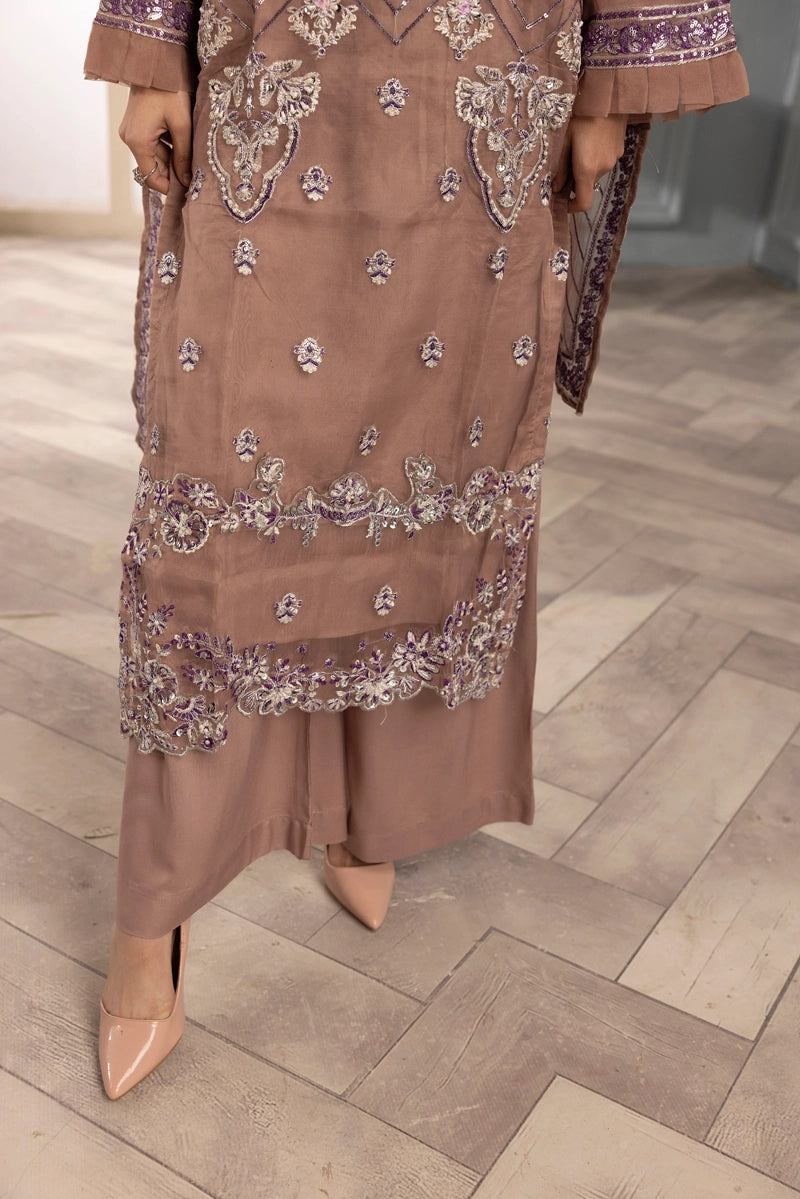 Brown embroidered dress worn by a person on a wooden floor.