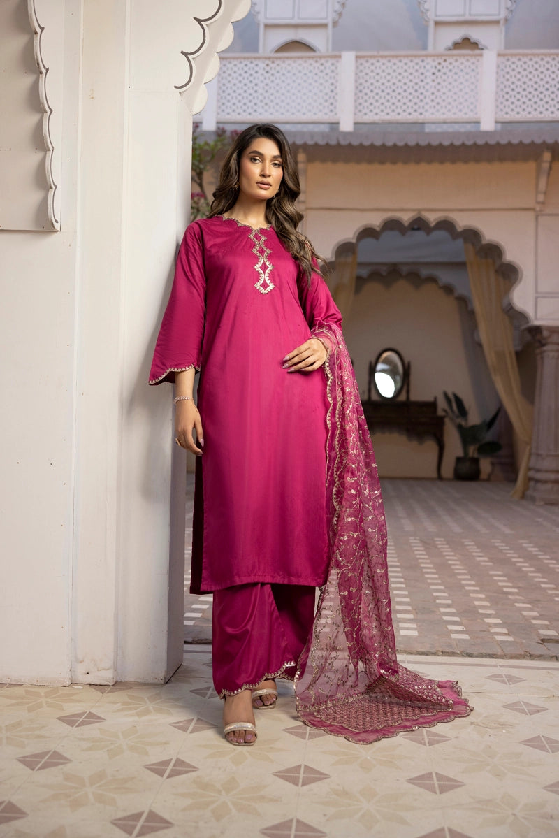 Woman in a pink traditional outfit standing in an ornate indoor setting.