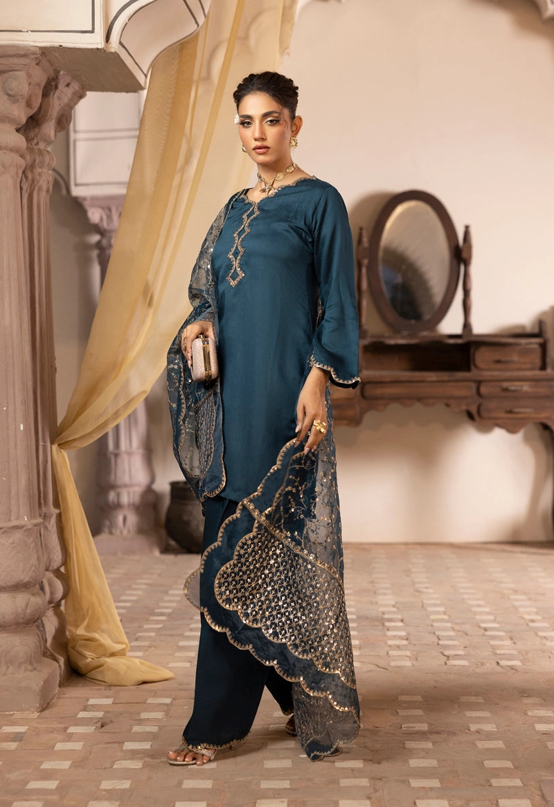 Woman in a blue traditional outfit holding a handbag in an indoor setting.