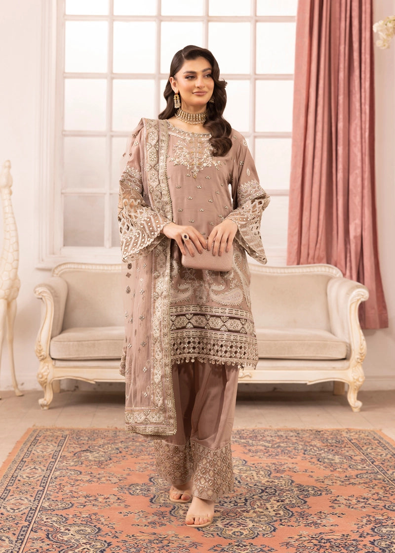 Woman in a traditional outfit standing in a decorated room with a sofa and pink curtains.