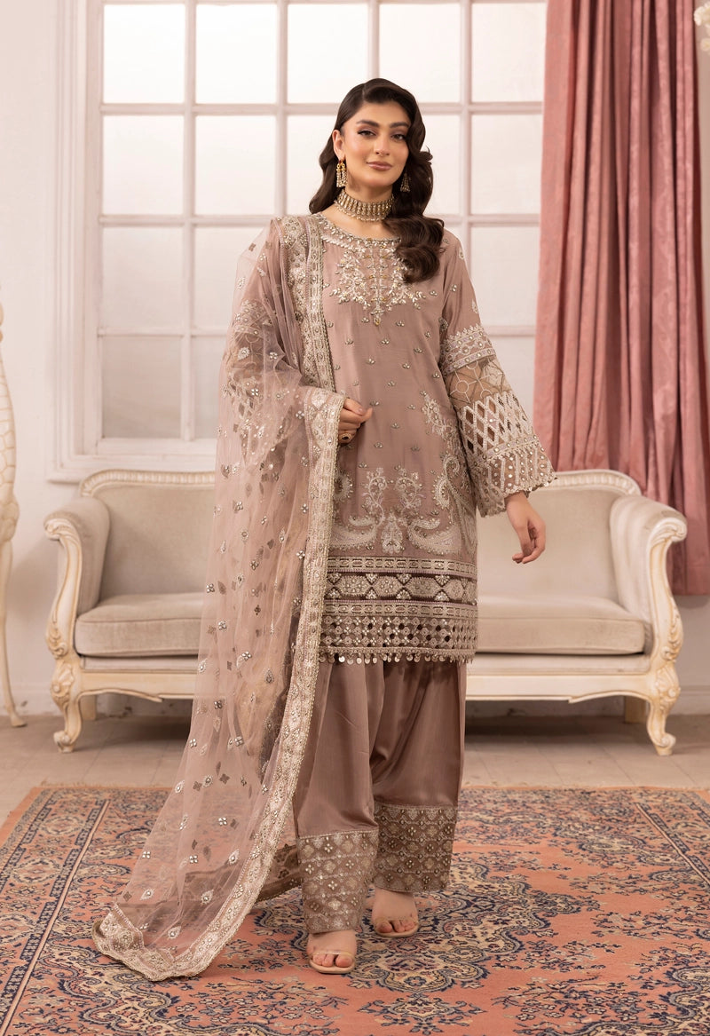 Woman in traditional embroidered outfit standing in a decorated room with pink curtains and a sofa.