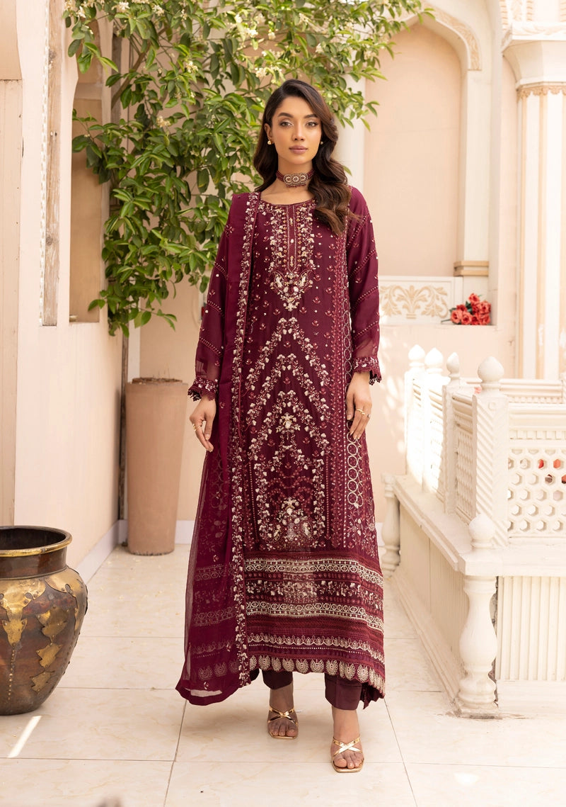Woman wearing a maroon embroidered traditional outfit in an elegant indoor setting.