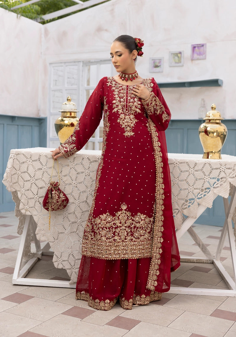 Woman in a red and gold traditional outfit standing by a table with a decorative setting.