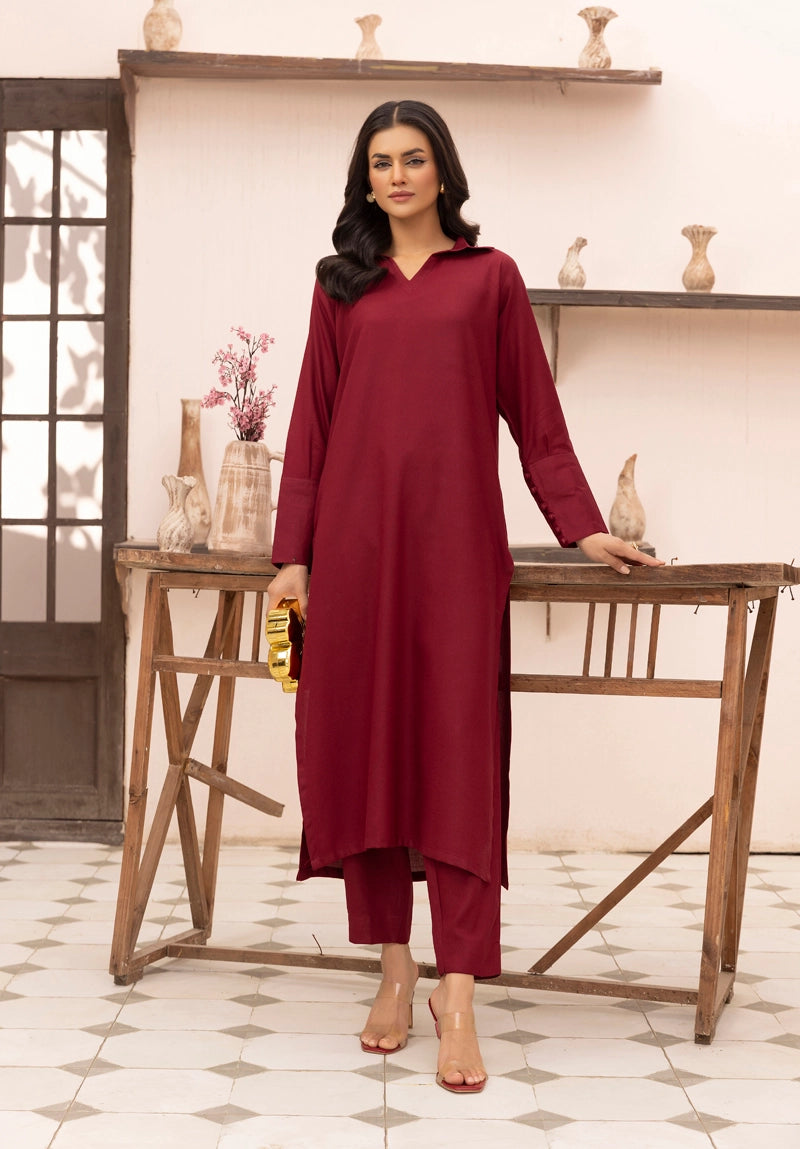 Woman wearing a maroon outfit standing in a room with wooden shelves and decor.