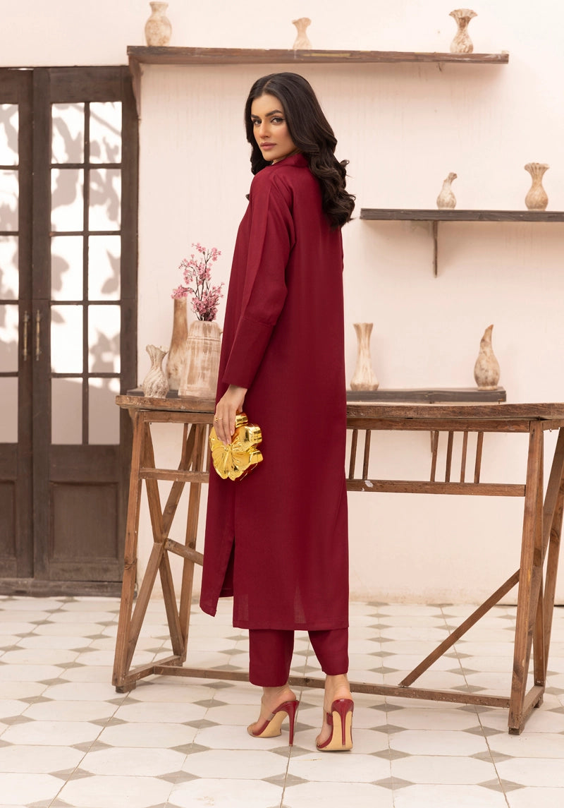 Woman in a red outfit standing in a room with wooden furniture and decorative items.