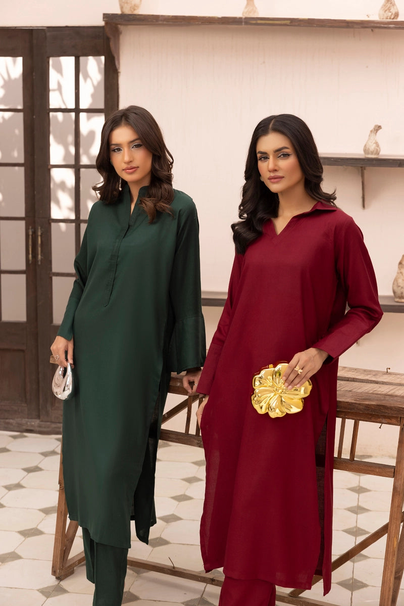 Two women wearing green and red outfits standing indoors.