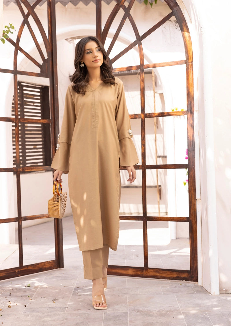 Woman wearing a beige outfit standing in a well-lit room with wooden architectural elements.