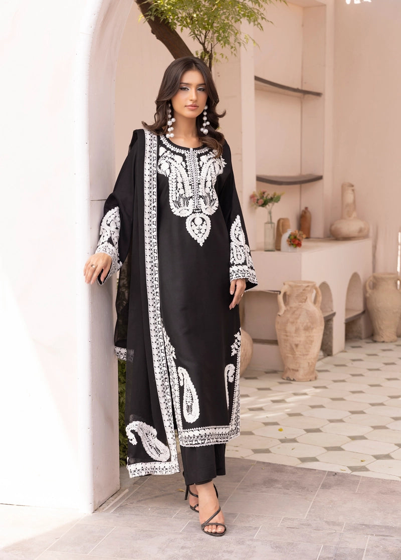 Woman wearing a black and white embroidered outfit in an indoor setting.