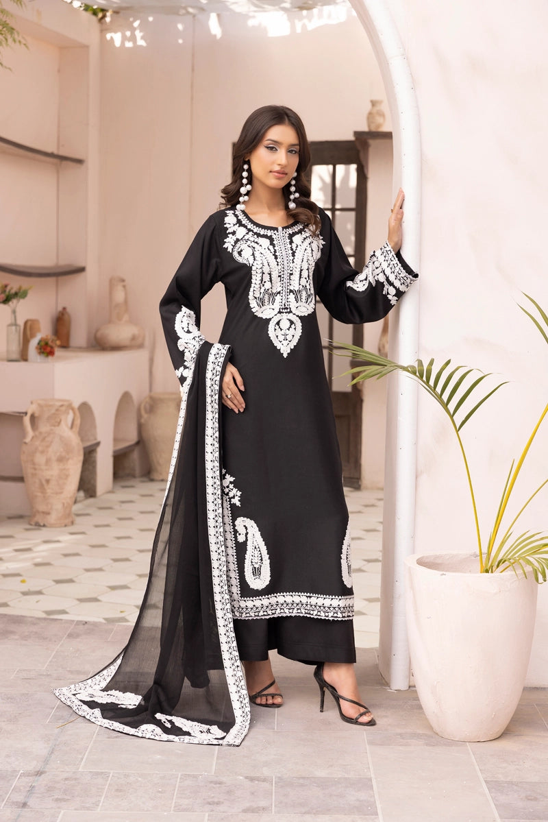 Woman in a black and white traditional outfit standing in a modern interior setting.