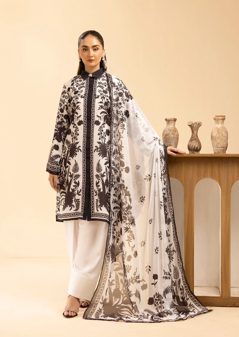 Woman wearing a black and white floral outfit with a matching dupatta, standing in front of a beige wall.