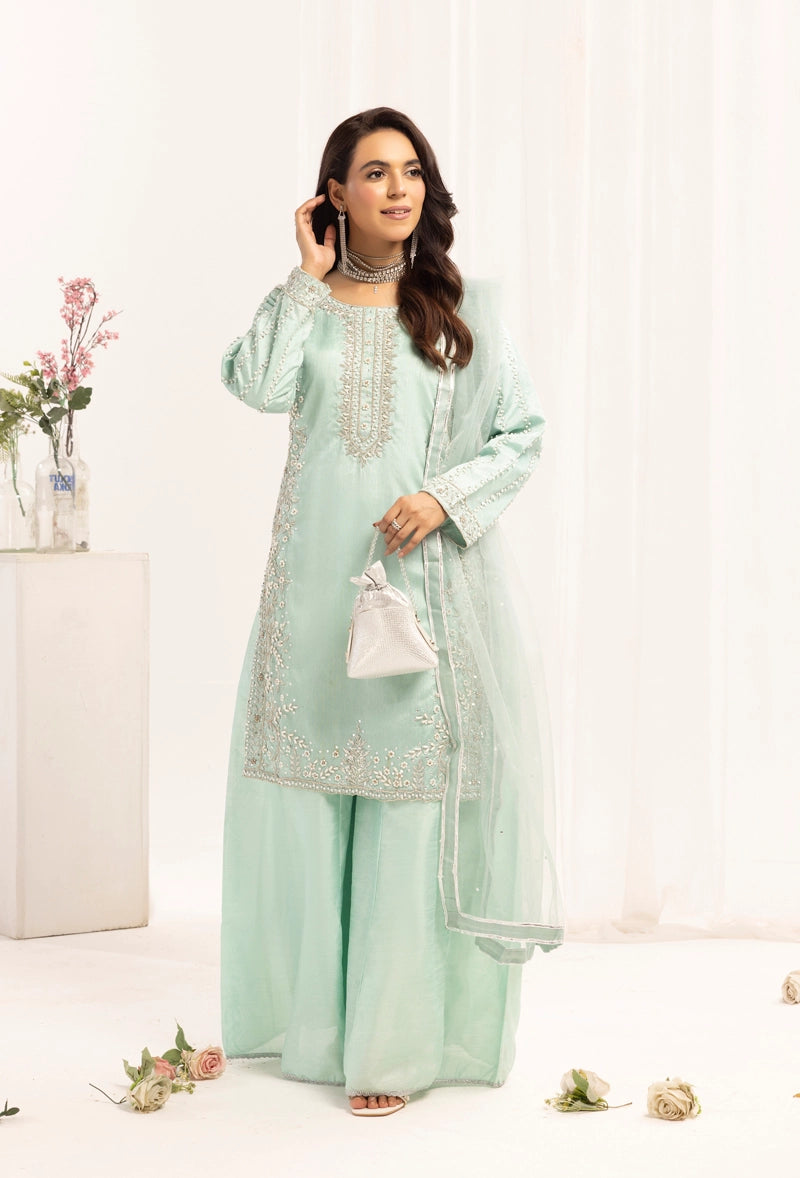 Woman wearing a light green traditional outfit with white embroidery on a white background