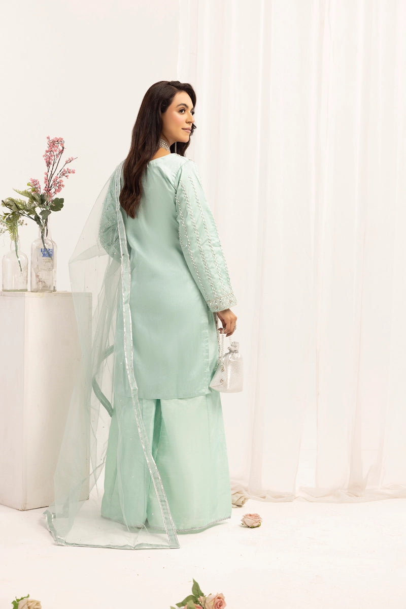 Woman wearing a light green traditional outfit with a white background