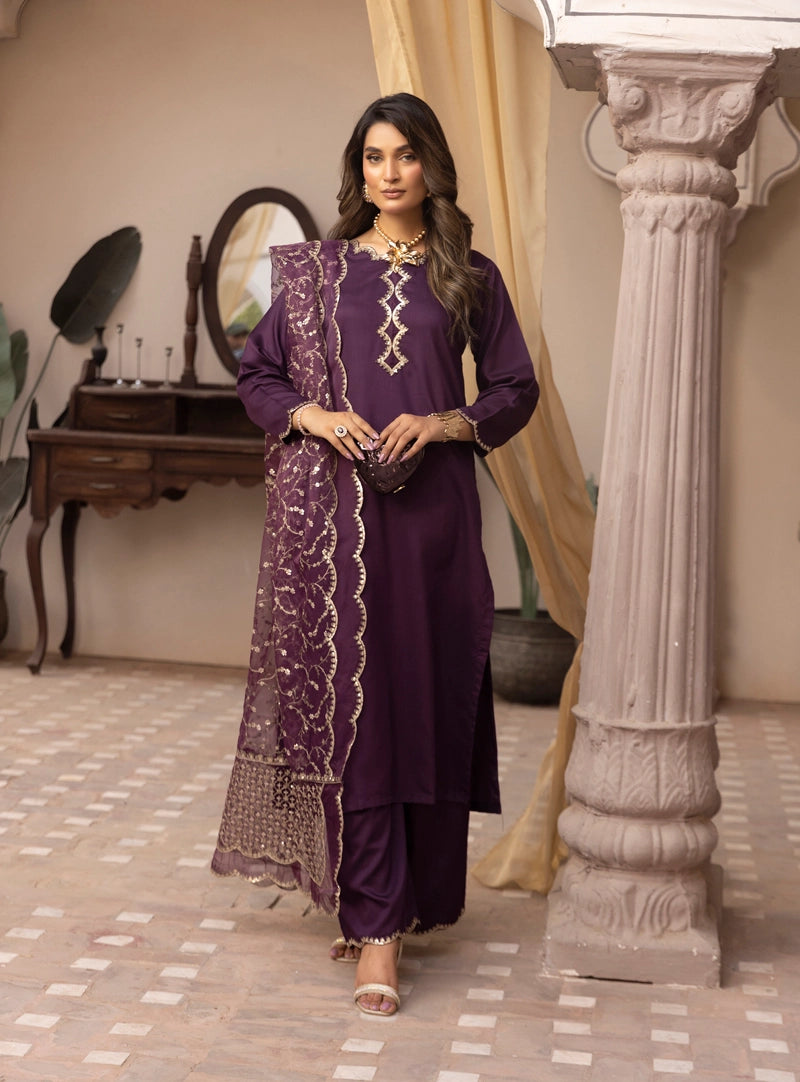 Woman in a purple traditional outfit standing in an elegant room with decorative elements.