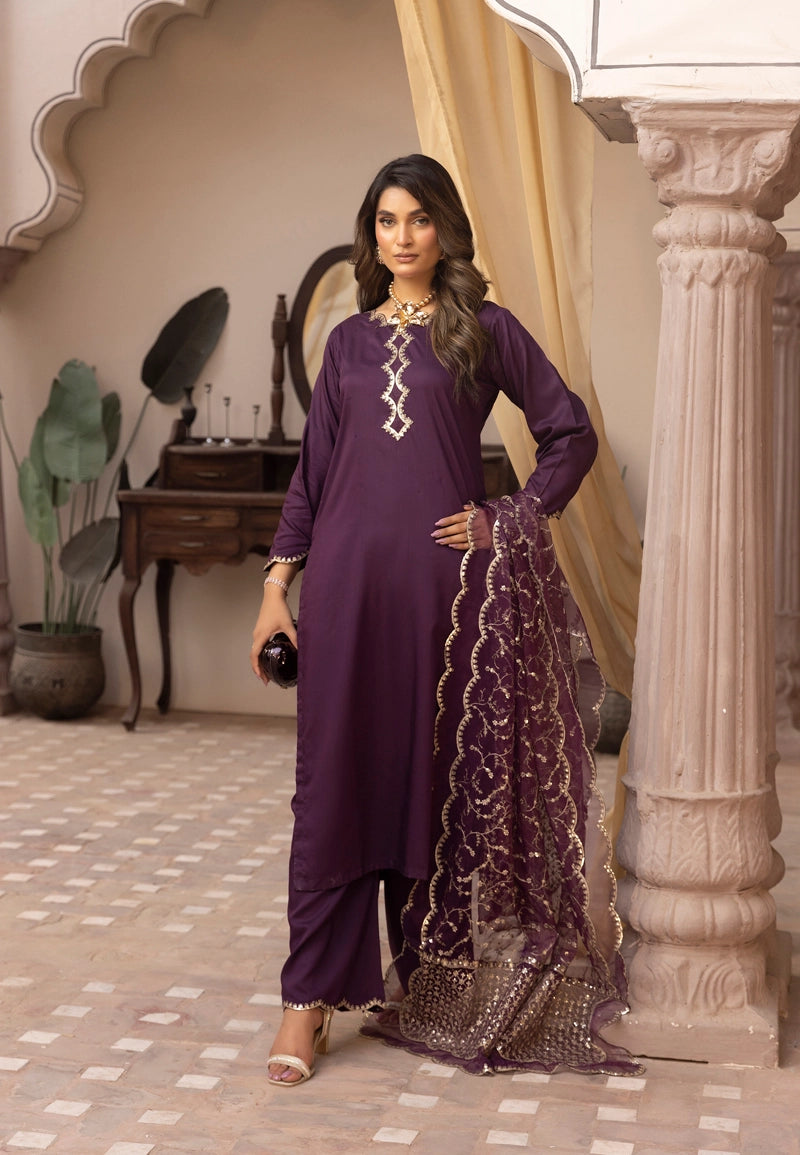 Woman in a purple traditional outfit with intricate designs in an ornate room.