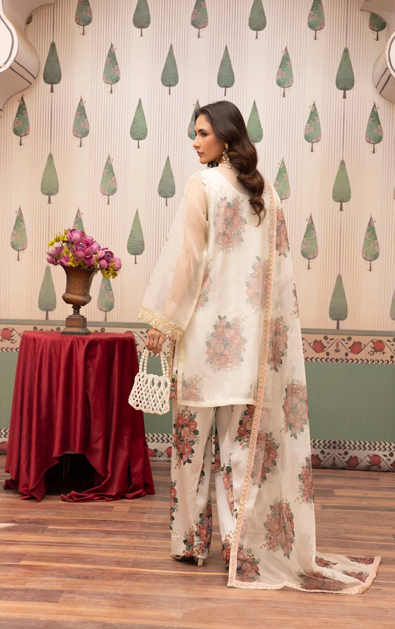 Woman in a floral outfit standing in a decorated room with a table and decorative wall.