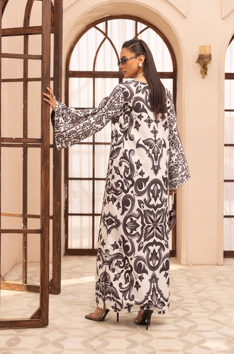 Woman in a black and white patterned dress standing in an elegant interior setting.