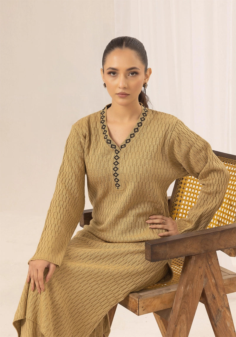 Woman wearing a beige traditional outfit sitting on a wooden chair.