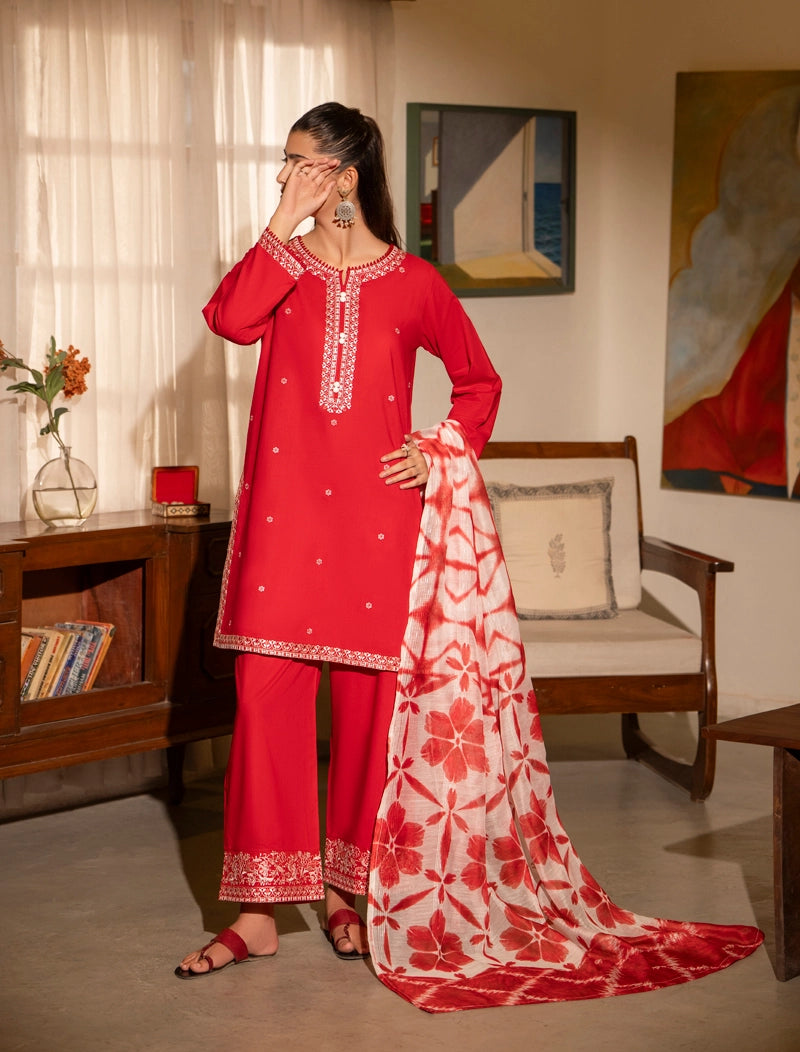 Woman in a red traditional outfit with white patterns in a living room setting.