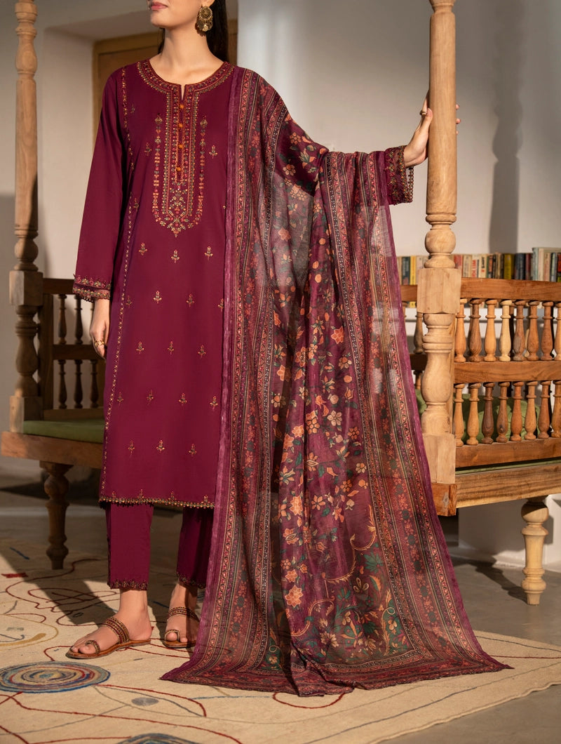 Woman wearing a traditional outfit with a purple dress and matching dupatta in a decorated room.