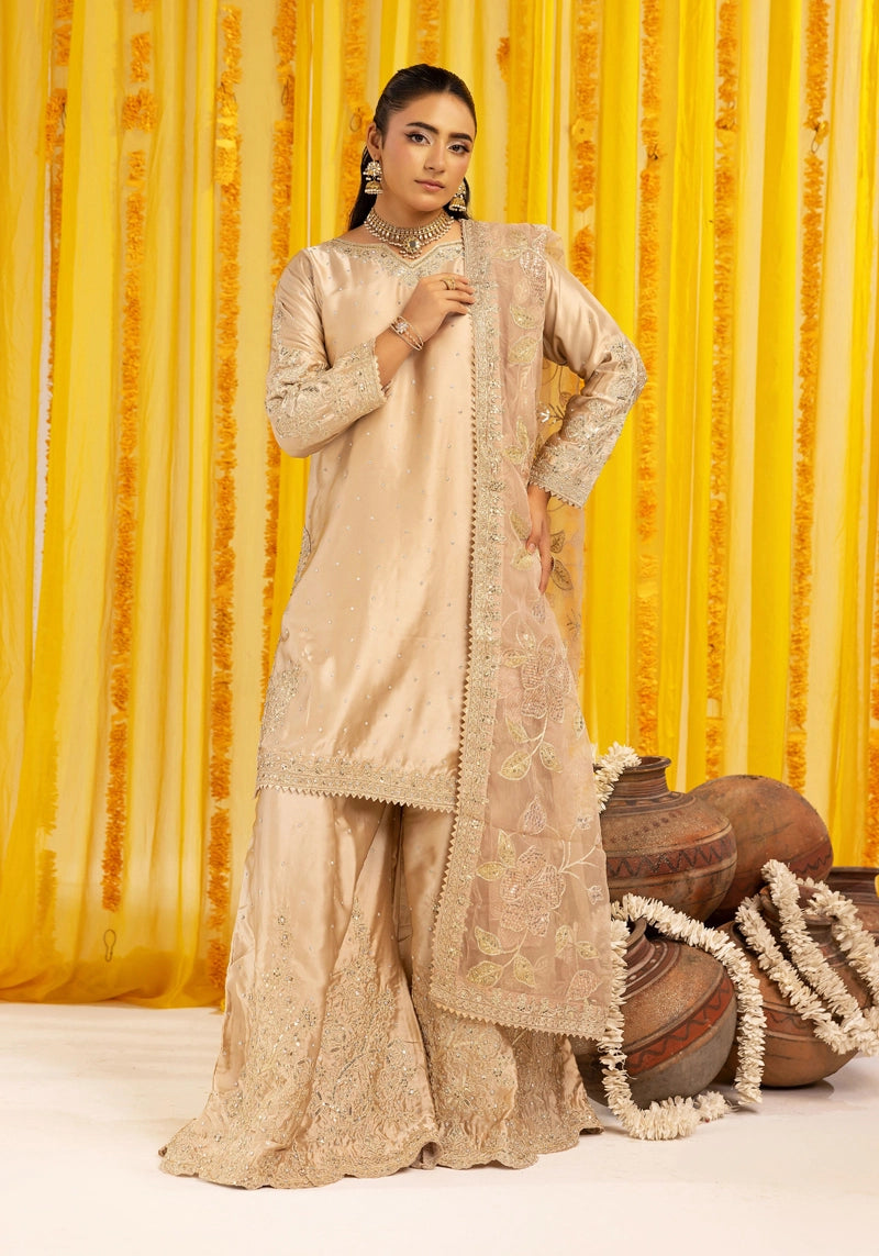 Woman in traditional beige outfit with floral patterns against a yellow curtain background