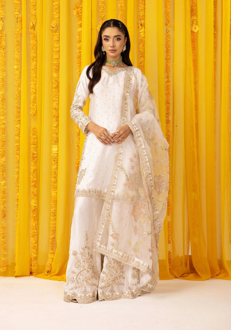 Woman in a white embroidered traditional outfit against a yellow curtain background