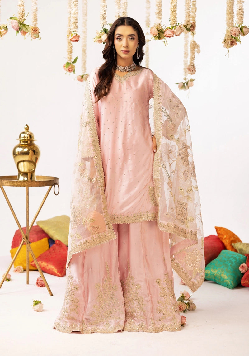 Woman in a pink traditional outfit with gold embroidery against a decorated background